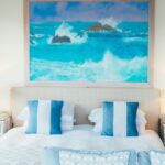 ocean with rocks painting on wall near bed