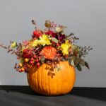 a pumpkin filled with lots of flowers on top of a table