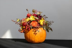 a pumpkin filled with lots of flowers on top of a table