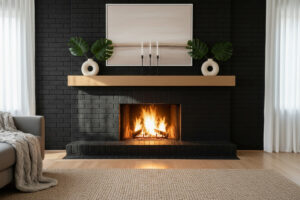 Warm minimalism: perfectly centered matte black brick surround, light oak floating mantel with donut vases and Monstera leaves, horizontal neutral abstract, roaring fire, beige woven rug—showcasing black brick fireplace with wood mantel and floor-to-ceiling black brick fireplace wall.