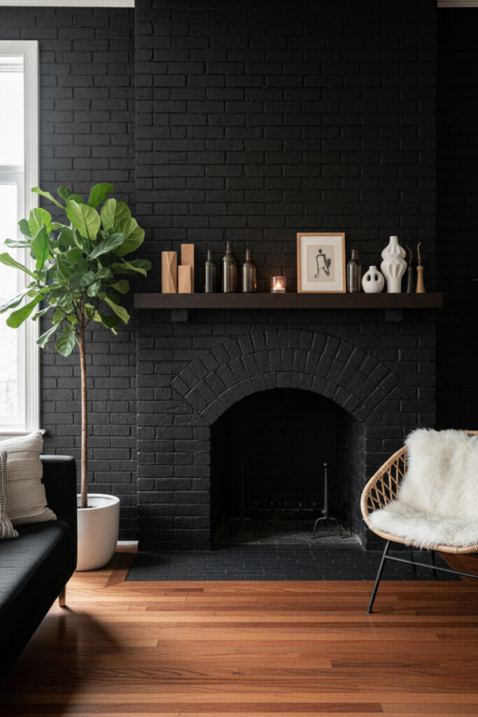High-contrast daylight on a charcoal-black arched firebox wall, dark wood shelf styled with ceramics and sketch, rattan chair with sheepskin, fiddle-leaf fig, and glossy hardwood floors.