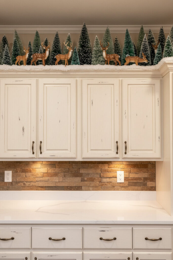 Distressed antique-white uppers topped with a winter wonderland of flocked trees and resin deer in faux snow.