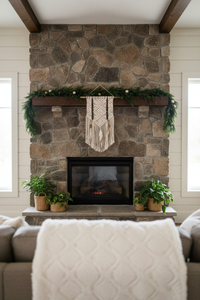 Fieldstone fireplace with evergreen swag and cream macramé tassels; plants and soft daylight create relaxed Boho holiday mantel decor, one of the best Christmas mantel garland ideas on a budget.