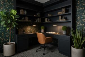 Forest green wallpapered workspace with botanical patterns, brass task lamps, and taupe leather chair showing refined dark home office ideas.