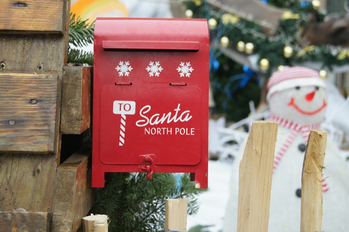 A red mailbox sitting next to a christmas tree